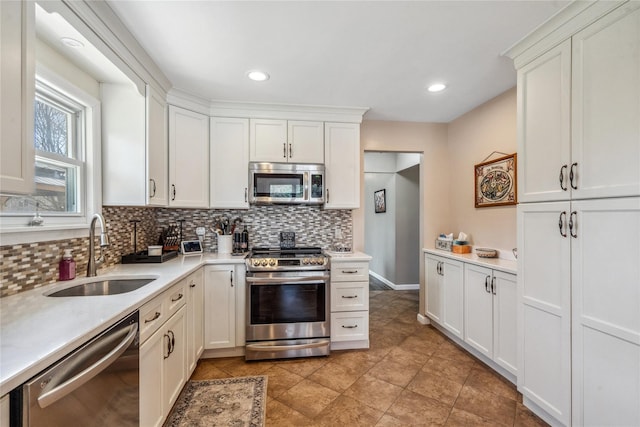 kitchen featuring white cabinetry, light countertops, backsplash, a sink, and appliances with stainless steel finishes