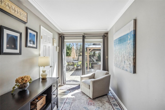 sitting room featuring ornamental molding, baseboards, and wood finished floors