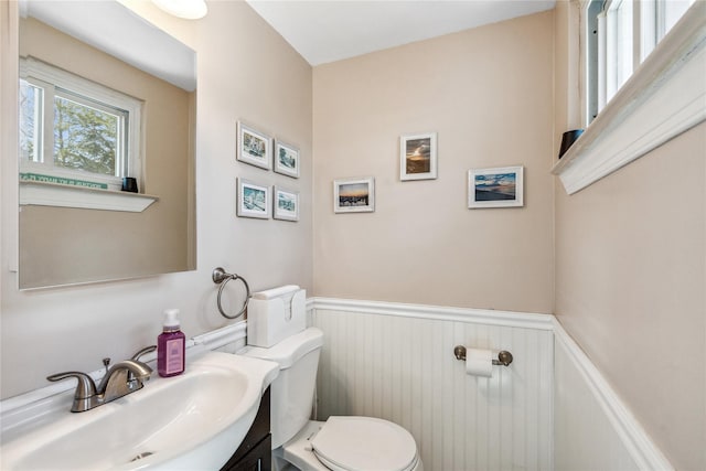 half bath with toilet, vanity, and wainscoting