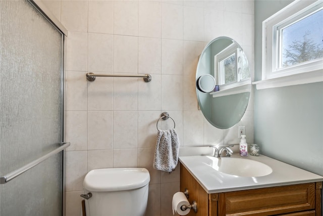 bathroom featuring toilet, vanity, an enclosed shower, and tile walls