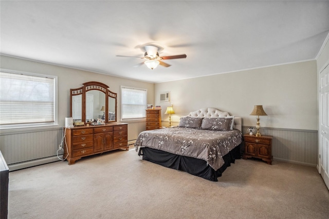 bedroom with a ceiling fan, a baseboard heating unit, wainscoting, and light carpet
