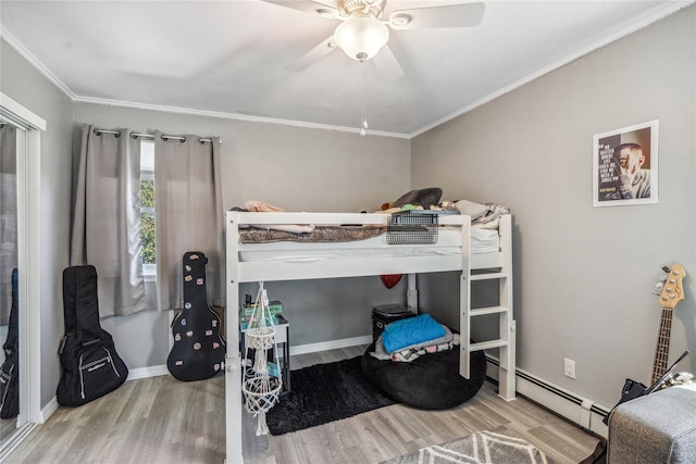 bedroom with crown molding, a ceiling fan, wood finished floors, baseboard heating, and baseboards