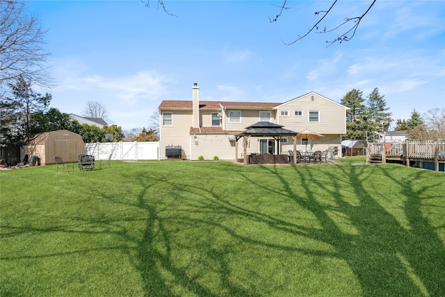 back of house with a lawn, an outdoor structure, a gazebo, and a storage shed