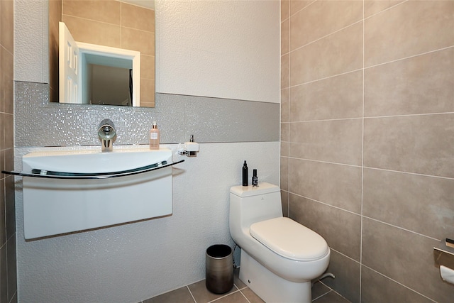 half bathroom with toilet, tile walls, tile patterned floors, and vanity