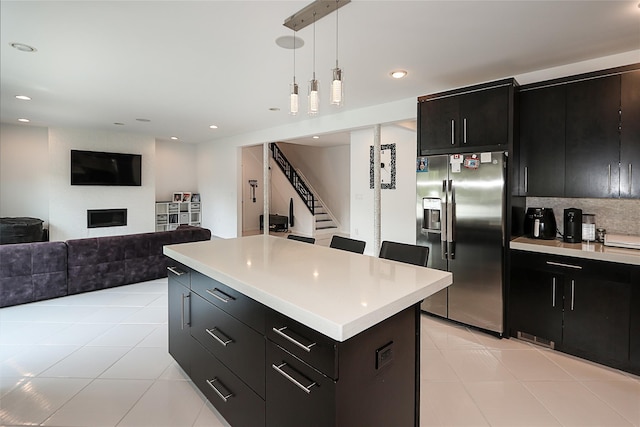 kitchen featuring stainless steel fridge with ice dispenser, dark cabinetry, light countertops, pendant lighting, and light tile patterned floors