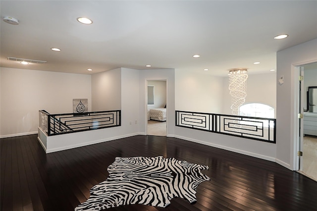 hall with an upstairs landing, hardwood / wood-style flooring, recessed lighting, baseboards, and a chandelier