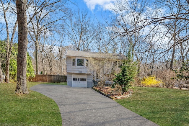view of front facade with fence, an attached garage, driveway, and a front yard