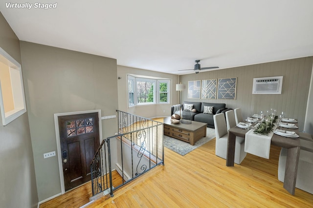 living room featuring a ceiling fan, wood finished floors, and a wall mounted AC