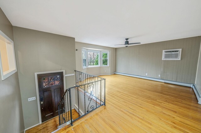 spare room with a wall mounted AC, wood finished floors, baseboard heating, and baseboards