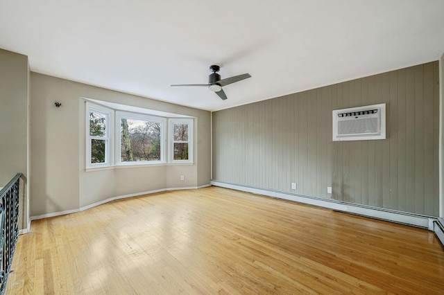 unfurnished living room with light wood-type flooring, baseboards, an AC wall unit, ceiling fan, and a baseboard radiator