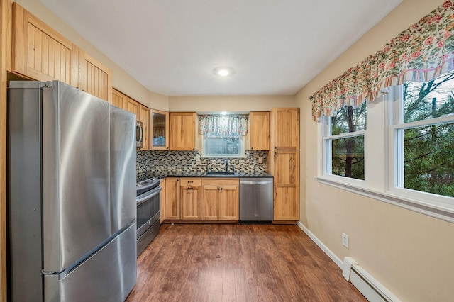 kitchen with dark wood-style floors, tasteful backsplash, dark countertops, baseboard heating, and appliances with stainless steel finishes