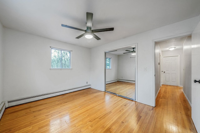 unfurnished bedroom featuring a closet, baseboards, a ceiling fan, a baseboard radiator, and wood finished floors