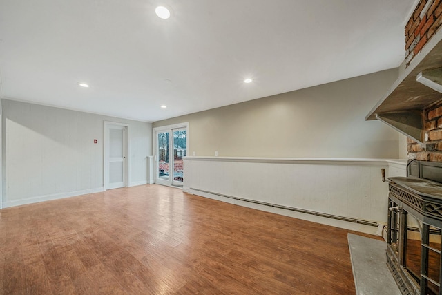 unfurnished living room with a baseboard heating unit, a wood stove, wood finished floors, and recessed lighting