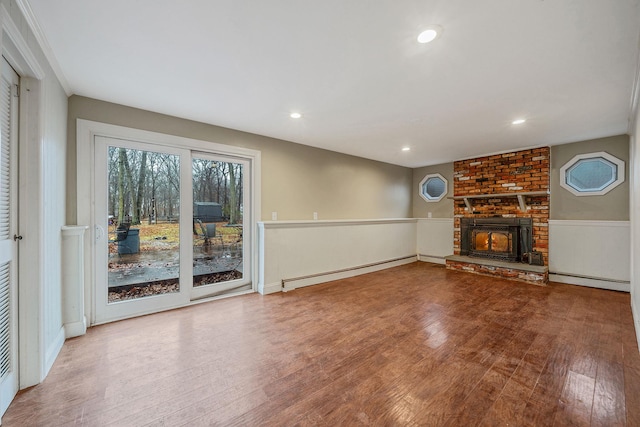 unfurnished living room featuring a brick fireplace, recessed lighting, wood finished floors, and baseboard heating