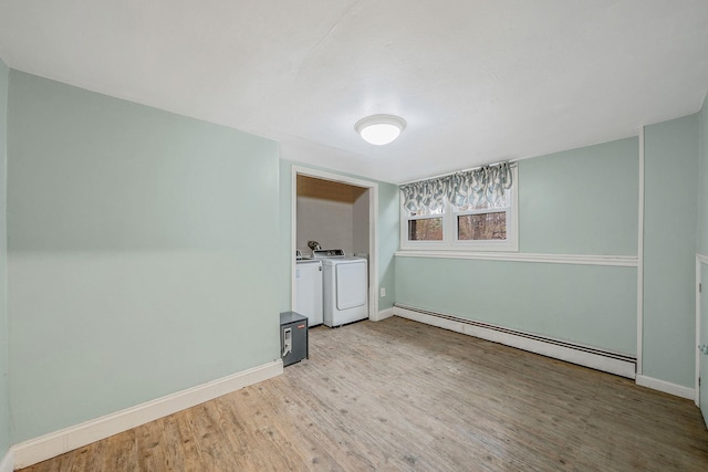 spare room featuring washing machine and dryer, baseboards, baseboard heating, and wood finished floors