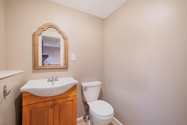 half bathroom featuring vanity, baseboards, and toilet