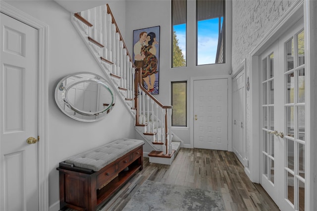 entryway with french doors, stairway, a high ceiling, and wood finished floors