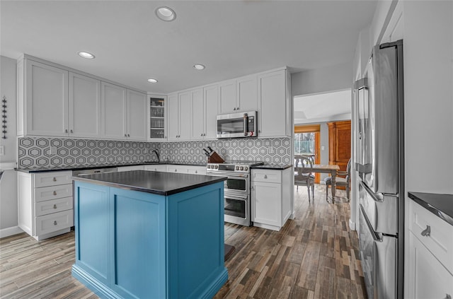 kitchen featuring dark wood finished floors, dark countertops, and appliances with stainless steel finishes