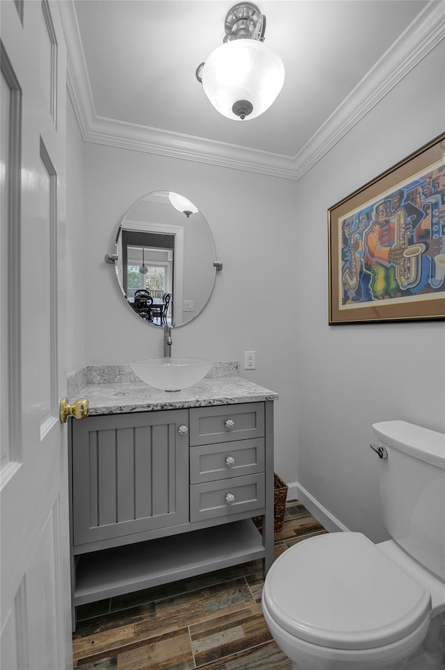 bathroom featuring vanity, toilet, ornamental molding, baseboards, and wood finished floors