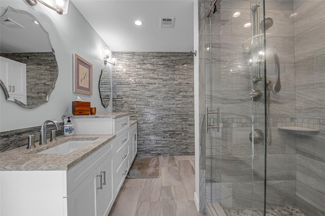 full bath with vanity, a stall shower, tile walls, and visible vents