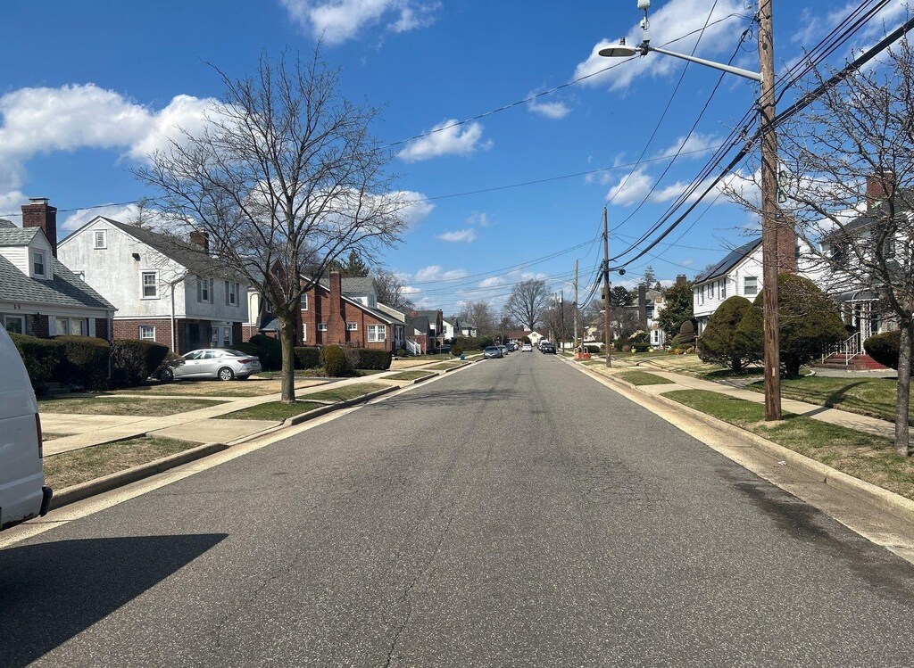 view of street featuring curbs, street lights, sidewalks, and a residential view