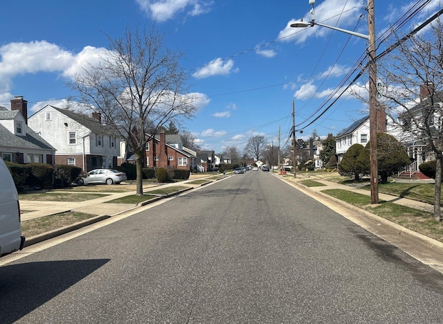 view of street featuring curbs, street lights, sidewalks, and a residential view