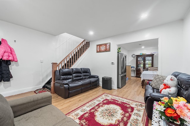 living area featuring baseboards, stairs, recessed lighting, and light wood-type flooring