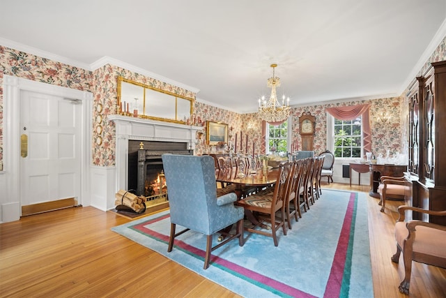 dining room with an inviting chandelier, wallpapered walls, a wainscoted wall, and light wood-style floors