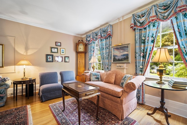living area with baseboards, crown molding, a healthy amount of sunlight, and wood finished floors