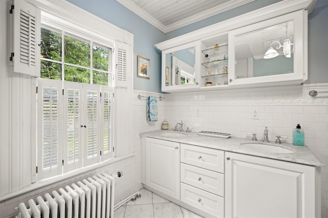full bathroom with radiator, double vanity, ornamental molding, and a sink
