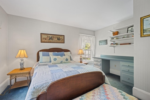 bedroom featuring built in study area, baseboards, and dark colored carpet
