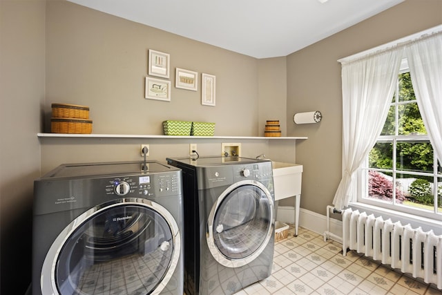 clothes washing area with laundry area, baseboards, radiator heating unit, and separate washer and dryer