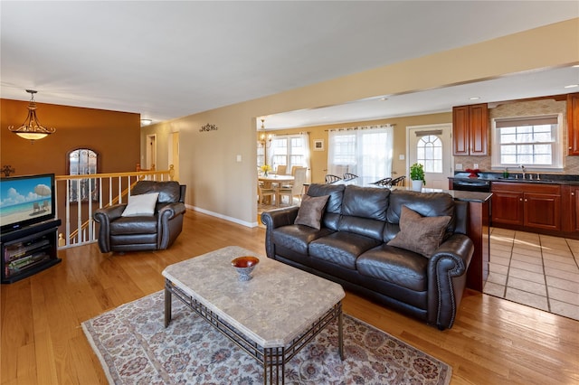 living room featuring light wood finished floors, baseboards, and a notable chandelier