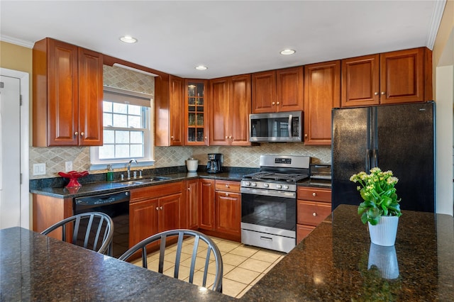 kitchen featuring backsplash, light tile patterned floors, a sink, black appliances, and glass insert cabinets