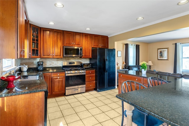 kitchen with a sink, tasteful backsplash, light tile patterned flooring, appliances with stainless steel finishes, and ornamental molding