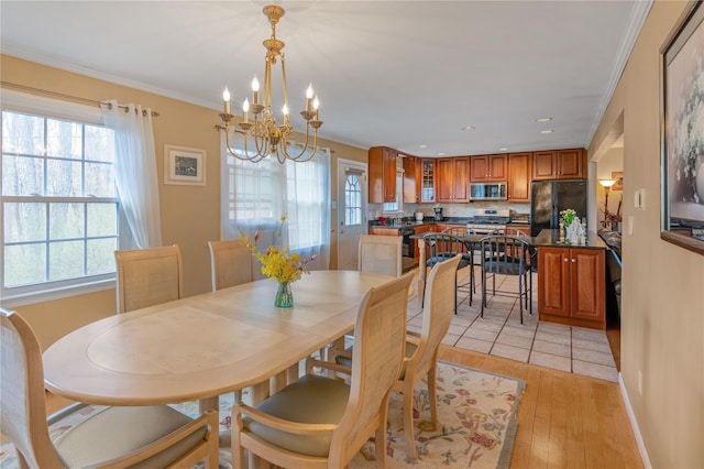 dining room with a chandelier, light wood-style flooring, a healthy amount of sunlight, and crown molding