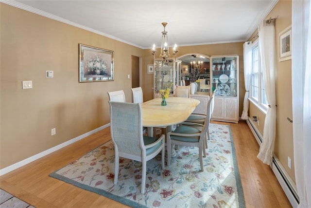 dining room with light wood finished floors, baseboards, an inviting chandelier, baseboard heating, and crown molding