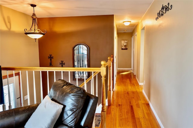 hallway with baseboards, light wood-style floors, and an upstairs landing