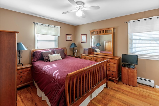 bedroom featuring a baseboard radiator, light wood finished floors, a ceiling fan, and multiple windows