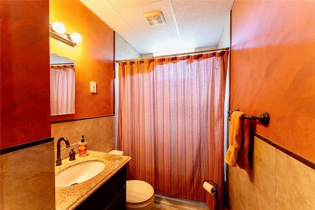 full bathroom with visible vents, toilet, vanity, a shower with curtain, and tile walls