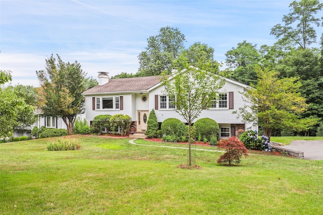 raised ranch with a front lawn and a chimney