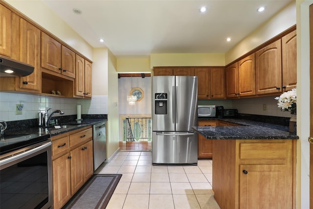 kitchen featuring decorative backsplash, light tile patterned flooring, dark stone counters, a sink, and stainless steel appliances