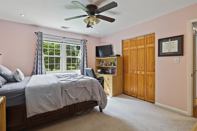 bedroom with ceiling fan, visible vents, light carpet, and a closet