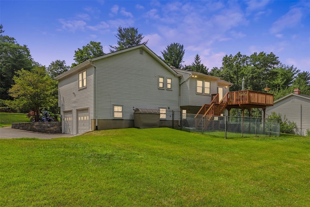 rear view of house with a lawn, a deck, fence, an attached garage, and stairs
