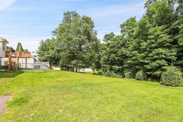 view of yard with a deck, fence, and stairs