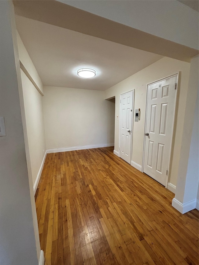 spare room featuring wood-type flooring and baseboards
