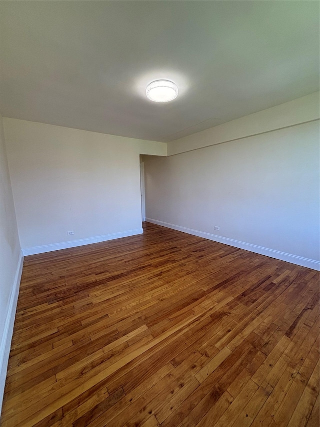 empty room featuring wood-type flooring and baseboards