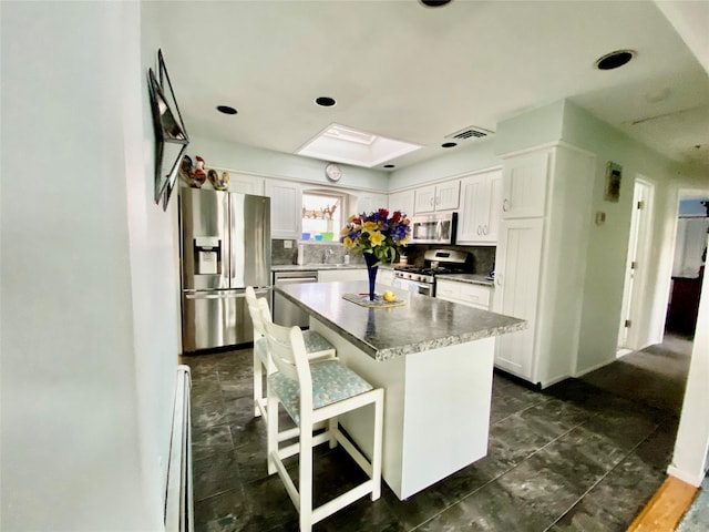 4081 Massachusetts Ave, Island Park, NY 11558 - kitchen featuring a kitchen island, white cabinetry, stainless steel appliances, visible vents, and decorative backsplash