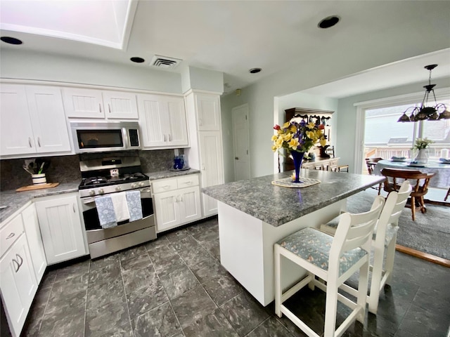 4081 Massachusetts Ave, Island Park, NY 11558 - kitchen with stone counters, backsplash, white cabinetry, a center island, and stainless steel appliances