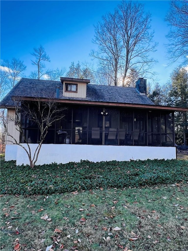 rear view of house with a sunroom and a lawn